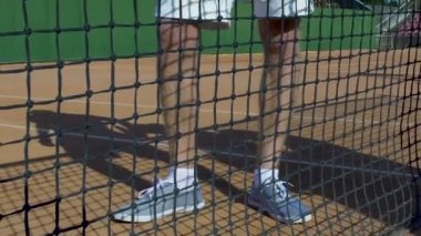 Sporcu adam beyaz spor giyim ayakta raket ile net yakınındaki tenis eğitim