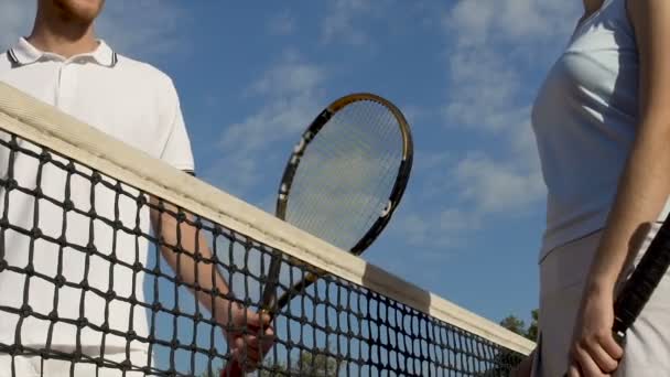 Тенісні гравці рукостискаються після матчу на фоні блакитного неба, змагання — стокове відео