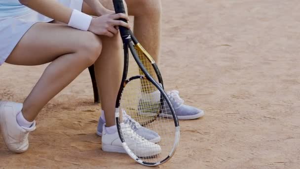 Pies de tenistas masculinos y femeninos sentados en la cancha, esperando resultados — Vídeo de stock