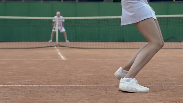 Socios del club de tenis jugando conjunto, mujer sirviendo pelota, vista trasera cámara lenta — Vídeos de Stock