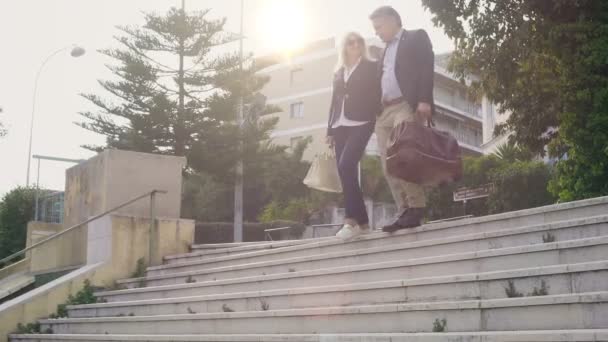 Happy couple with bags leaving hotel and going down the stairs, vacation — Stock Video