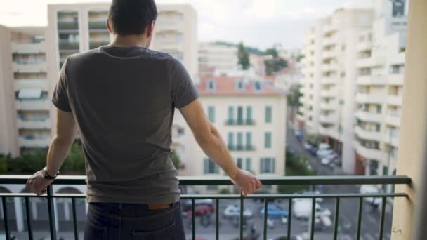 Masculino em pé na varanda e desfrutando de vista na rua após o dia de trabalho duro — Vídeo de Stock