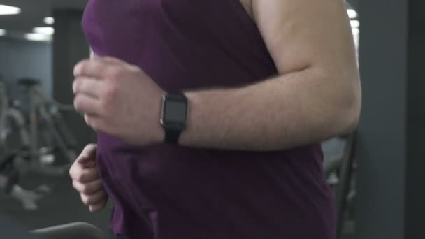 自信的运动员与 smartwatch 运行在跑步机控制他的指示器 — 图库视频影像