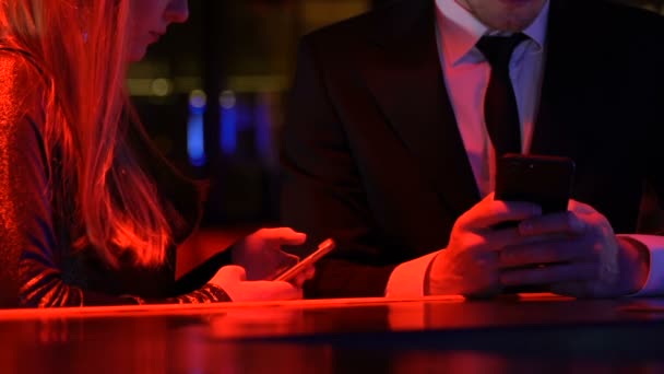 Pareja joven indiferente pasar tiempo con los teléfonos inteligentes en el bar, adicción gadget — Vídeos de Stock