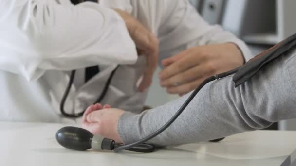Médecin masculin vérifiant la pression artérielle des patients féminins à l'examen, clinique — Video