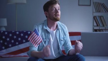 ABD bayrağı sallayarak ve seçim sonuçları on tv ev izlerken duygusal Amerikalı adam