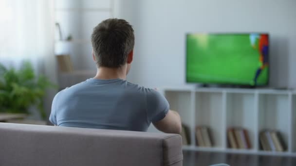 Joven viendo el partido de fútbol en casa, criticando al equipo de fútbol por su derrota — Vídeos de Stock