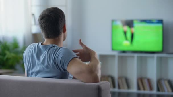 Футбольний фанат їсть попкорн, критикуючи гравців по телевізору, навчаючи, як забити — стокове відео