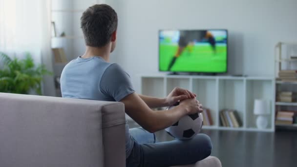 Сторонник футбольной команды смотрит игру по телевизору дома, недовольный результатом матча — стоковое видео