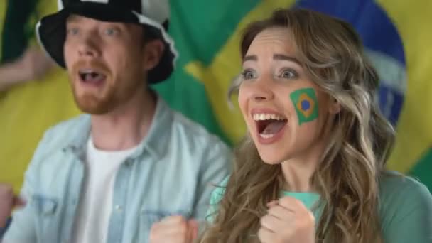 Бразильские болельщики смотрят футбольный матч по телевизору, празднуют победу команды — стоковое видео