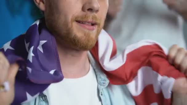 Gelukkig man wuivende Amerikaanse vlag, kijken naar sport concurrentie, juichen team — Stockvideo