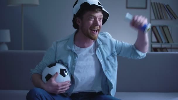 Vrolijke mannelijke ventilator met voetbal attributen kijken wedstrijd op tv thuis, overwinning — Stockvideo
