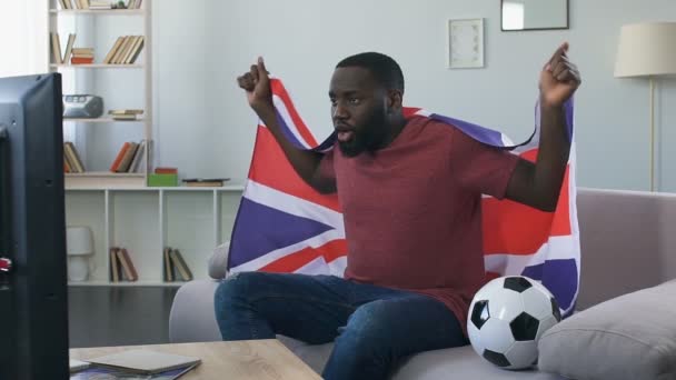 Tifosi britannici che fanno il tifo per la nazionale con bandiera sventolante, guardando la partita in casa — Video Stock