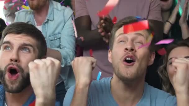 Confetti falling on football fans roaring about goal scored, happy for victory — Stock Video