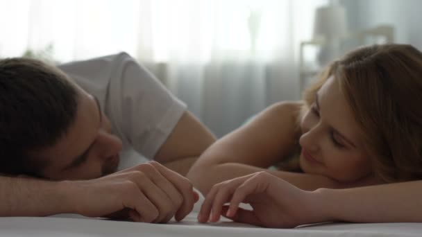 Boyfriend and girlfriend holding hands lying bed, looking with love, tenderness — Stock Video