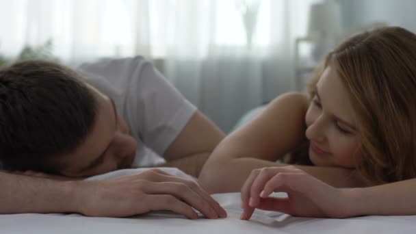 Juguetona joven mujer tomando tiernamente durmiendo marido mano, dulces relaciones — Vídeo de stock