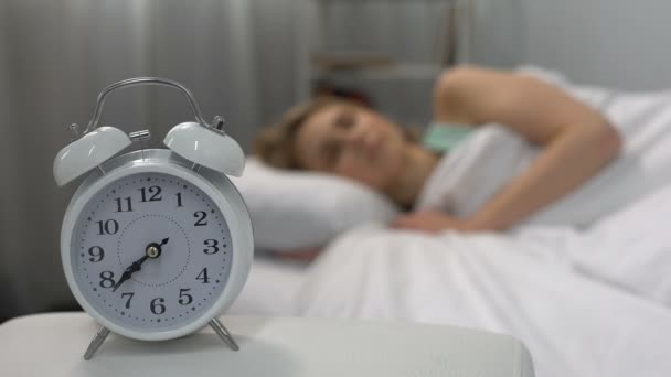 Звонит будильник, просыпается спящая женщина в постели, лень, самодисциплина — стоковое видео