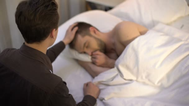 若い男の睡眠パートナーの頭をなでる、同性愛カップル、入札関係 — ストック動画