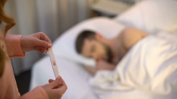 Woman holding positive pregnancy test, thinking over decision, feeling confused — Stock Video