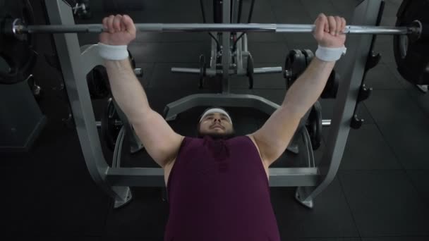 Chubby man unable to lift heavy barbell in gym during sport exercise, health — Stock Video