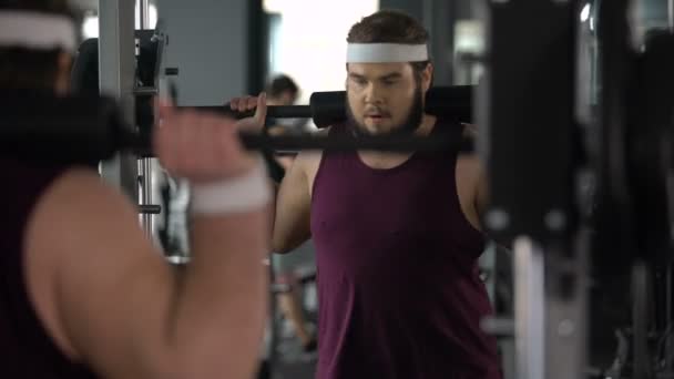 Membre du club de fitness faisant squats avec haltère, satisfait de ses progrès — Video