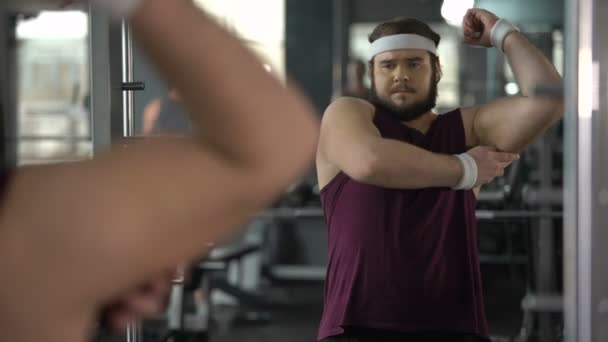 Hombre infeliz con sobrepeso mirando su reflejo espejo en el gimnasio, dieta y deporte — Vídeos de Stock