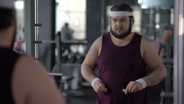 Lustiger fettleibiger Mann, der seine Bauchtaille mit Klebeband misst und zufrieden aussieht — Stockvideo