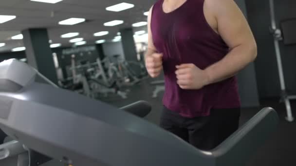 Hombre activo trotando en la cinta de correr para perder peso, haciendo ejercicio cardiovascular en el gimnasio — Vídeo de stock