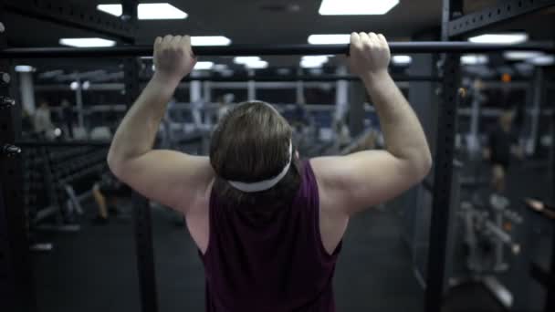 Człowiek stara się zaciągnąć jego ciężkie ciało, zwiększyć siłę mięśni, trening w siłowni — Wideo stockowe
