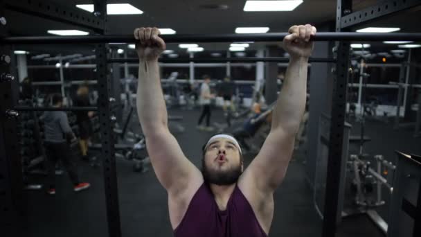 Hombre con sobrepeso tratando de tirar hacia arriba en la barra de deporte, músculos débiles del cuerpo, entrenamiento de gimnasio — Vídeos de Stock