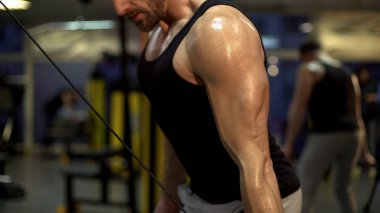 Tek kollu tempolu çekme-çıkışlar yapıyor spor salonunda çalışkan adam egzersiz bitirme 