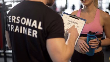 Kişisel antrenör haftalık spor salonunda, destek kadın müşteri ile yemek planı tartışıyor