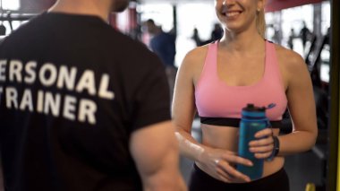 Spor hocası bitirdikten sonra konuşmaya gülümseyen kadın müşteri egzersiz, flört