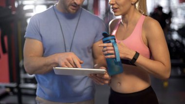 Egzersiz programı tablet kullanarak kişisel antrenör ile tartışırken spor kadın