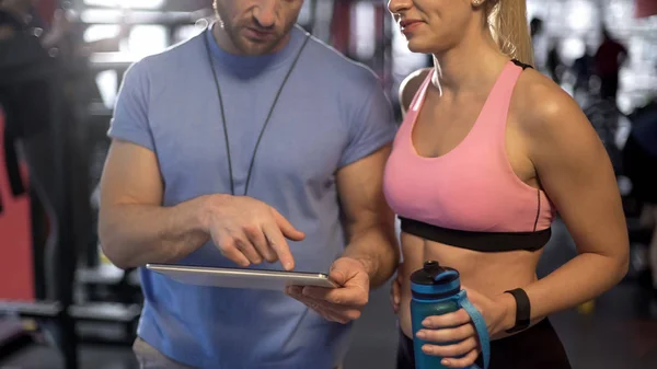 Healthy couple discussing workout plan in gym, defining future fitness goals