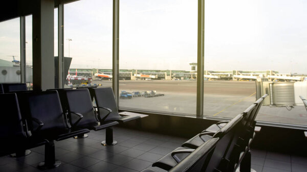 Empty seats of departure lounge airport, view of runway through window, travel