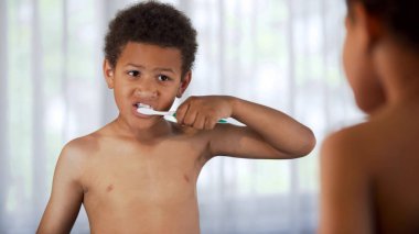 Küçük çocuk banyoda ayna, ağız hijyeni önünde Dişlerini fırçalıyor