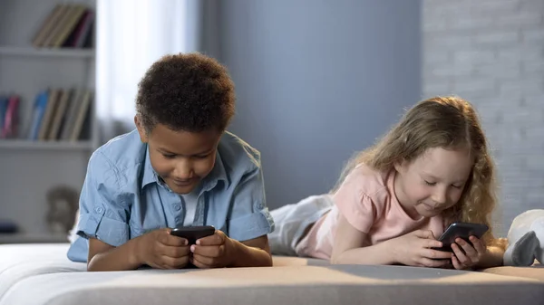 微笑的孩子玩在线游戏在移动应用 成瘾的小玩意 — 图库照片