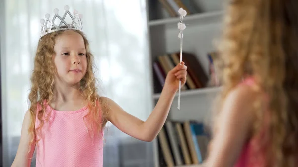 Little girl looking at mirror reflection, wearing fancy princess dress, magic