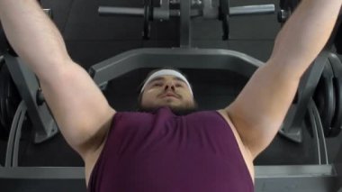 Spor salonunda, spor egzersizleri, kilo kaybı halter kaldırma tezgah üzerinde yatan şişko adam