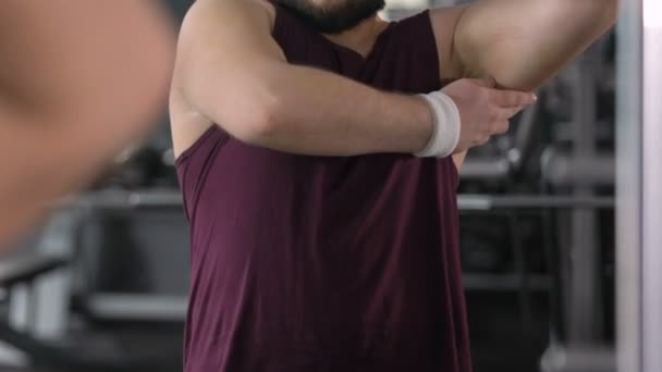 Gruby mężczyzna patrząc na ciało nadwaga i słabe mięśnie w siłowni odbicie lustrzane — Wideo stockowe