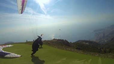 İzin almak paraglide şehir üzerinde arka deniz görünümü ile yokuş aşağı koşan adam