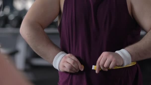 Homem gordo feliz que mede a barriga com fita no ginásio, realização da perda de peso, resultado — Vídeo de Stock
