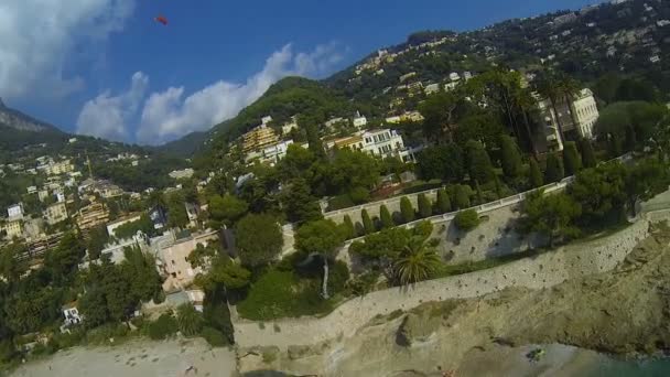 Personne parapente au-dessus du bord de mer après les bâtiments et les collines, se préparant à atterrir — Video