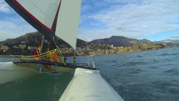 Windsurfing katamaran odejście od nadmorskie miasto z kilka osób na pokładzie — Wideo stockowe