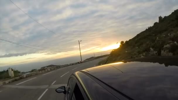 Автомобіль біжить швидко по шосе до заходу сонця, берегова лінія на гірському дні — стокове відео