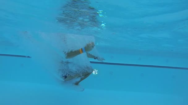 Man doing a cannonball into swimming pool and diving out, view from underwater — Stock Video