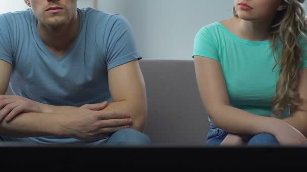 Couple sitting in front of TV and watching match, sad woman looking at man — Stock Video