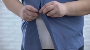 Obez erkek kadar düğmelerini mavi gömlek, ağırlık kaybı süreci, hormonal bozukluk.