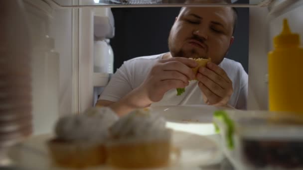 Uomo obeso tossicodipendente che mangia avidamente hamburger di notte, nutrizione malsana, dieta — Video Stock